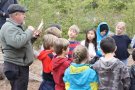 Waldführer erklärt Schülern etwas im Kreis