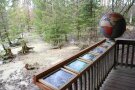 Holzsteg mit Klapptafeln und einem Holzglobus umgeben von einem Teich im Wald