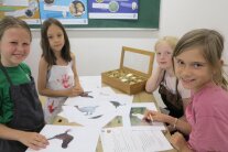 Kinder sitzen und stehen um einen Tisch