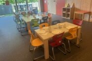 Raum mit 3 Esstischen für Kita-Kinder mit Geschirr eingedeckt
