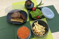 Verschiedene Mehrwegsystem-Schüsselchen mit vers. Lebensmitteln stehen auf einem Tisch