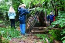 drei Kinder bauen im Sommer-Wald Tipis aus Ästen