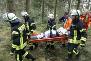 Feuerwehrmänner tragen eine Bahre aus dem Wald