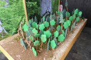 Holzbrettmodel mit Waldboden auf dem kleine Holzbäume und Tiere stehen