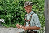 Ein sitzender Mann hält ein Holzstück in seinen Händen