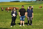 Drei Personen stehen auf einer Weide