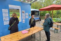 Drei Personen an einem Infostand