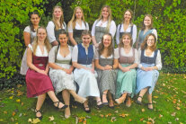 12 Personen in Dirndln auf einer Wiese